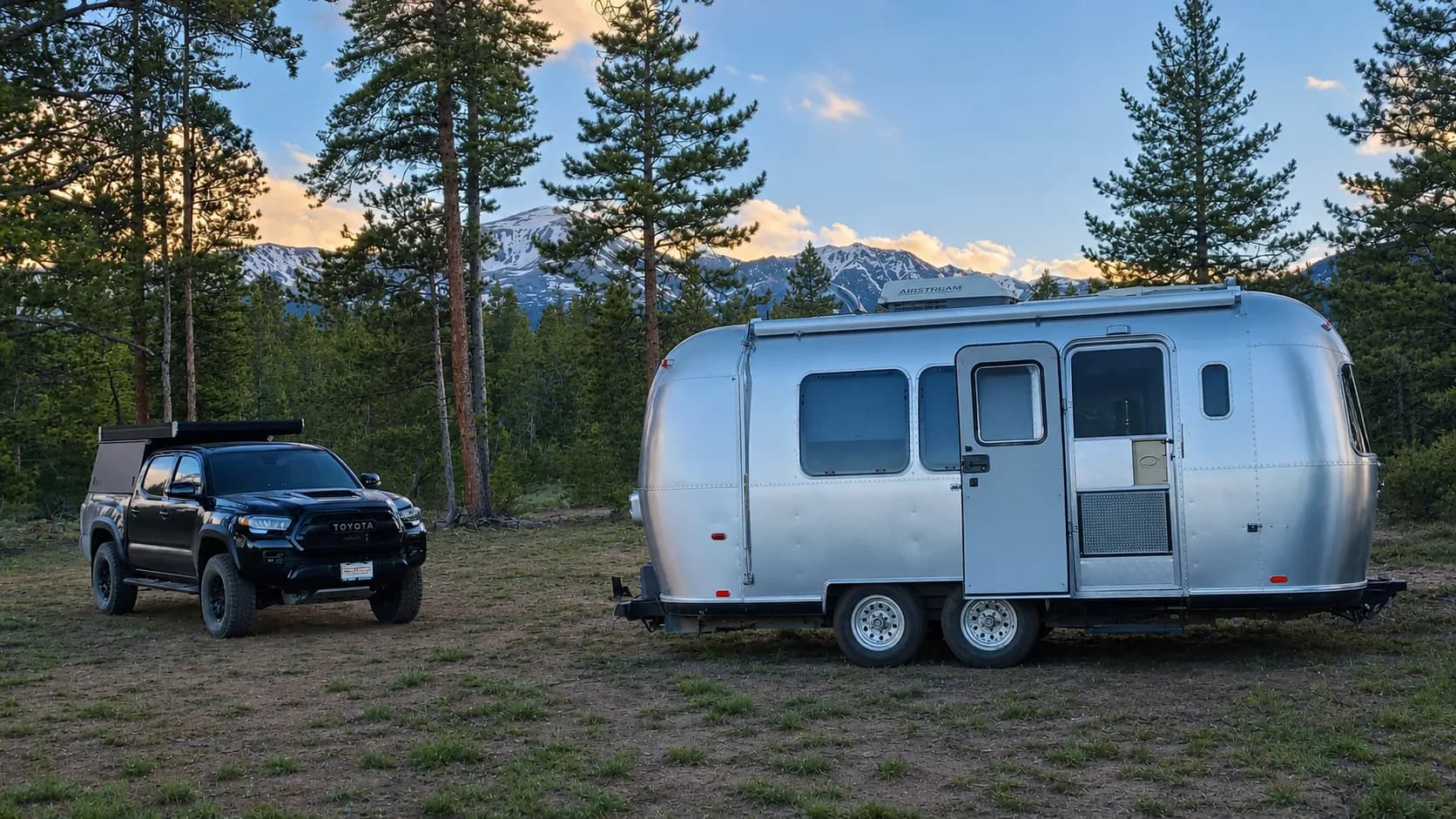 Airstream Safari at a wooded campsite with mountains in the background