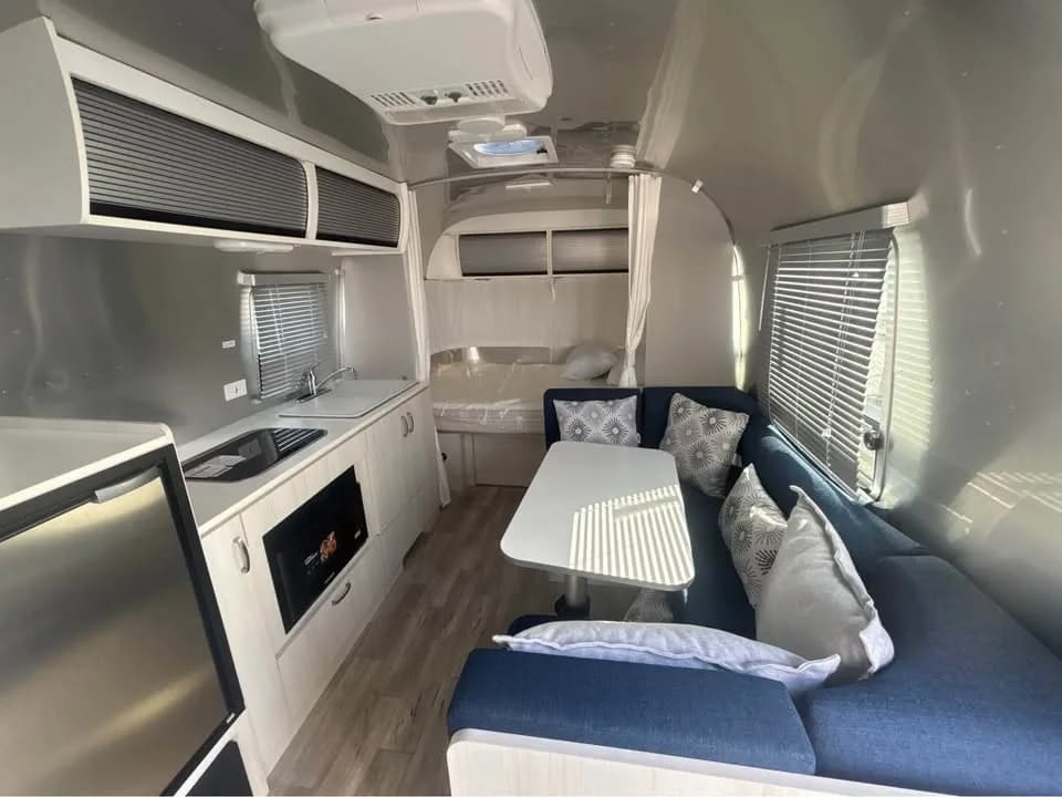 Airstream Bambi interior with a dinette, kitchen, and sleeping area
